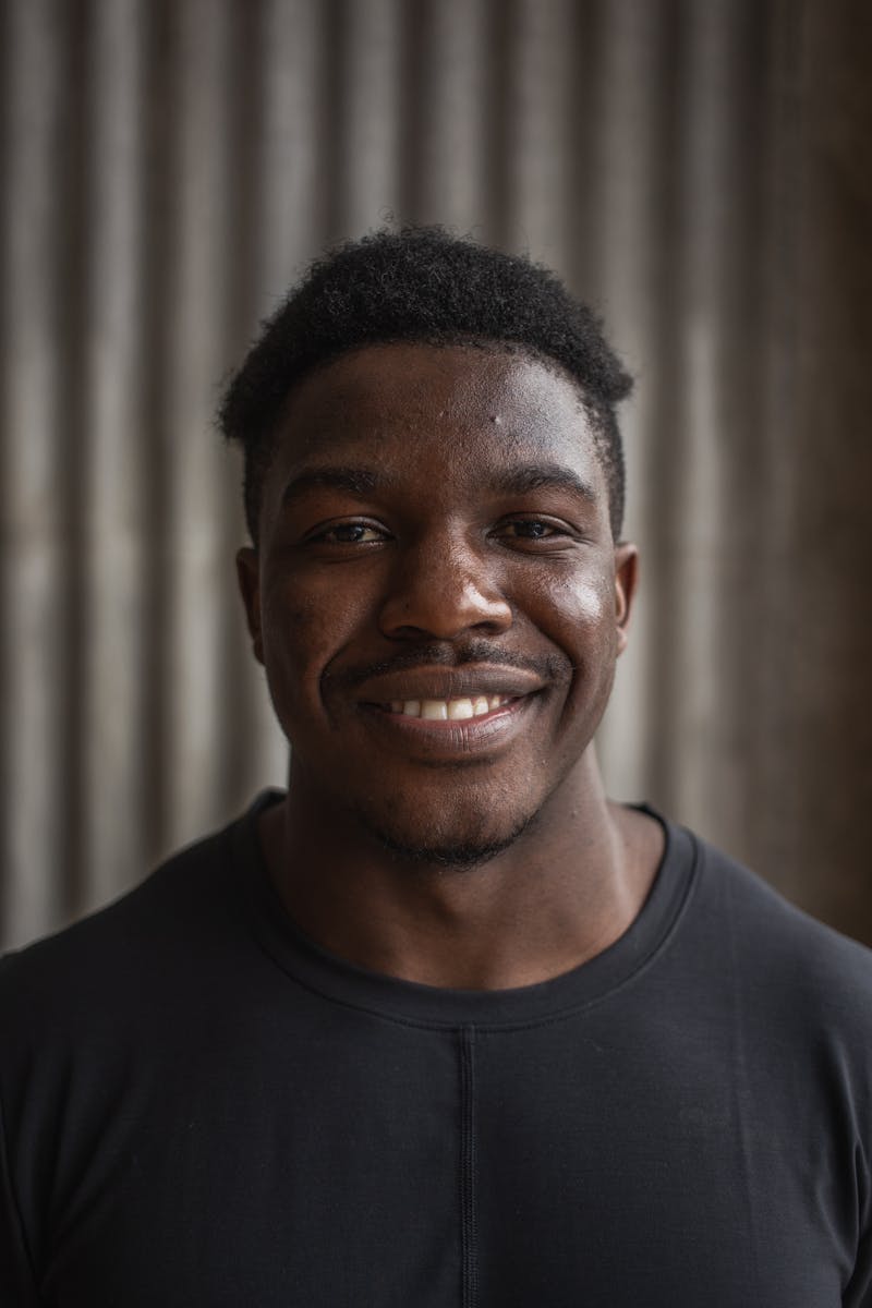 Portrait of a cheerful African American man smiling with a blurred gray background.